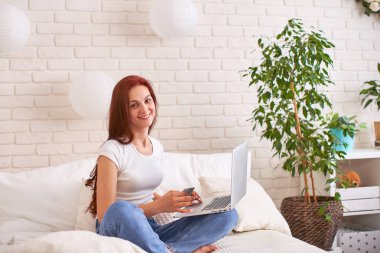 güzel genç kız gülümseyen ve bir banka kartı ve laptop tutarak 