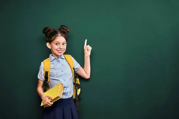 Petite fille, un élève pointe du doigt. positive écolière en t — Photo