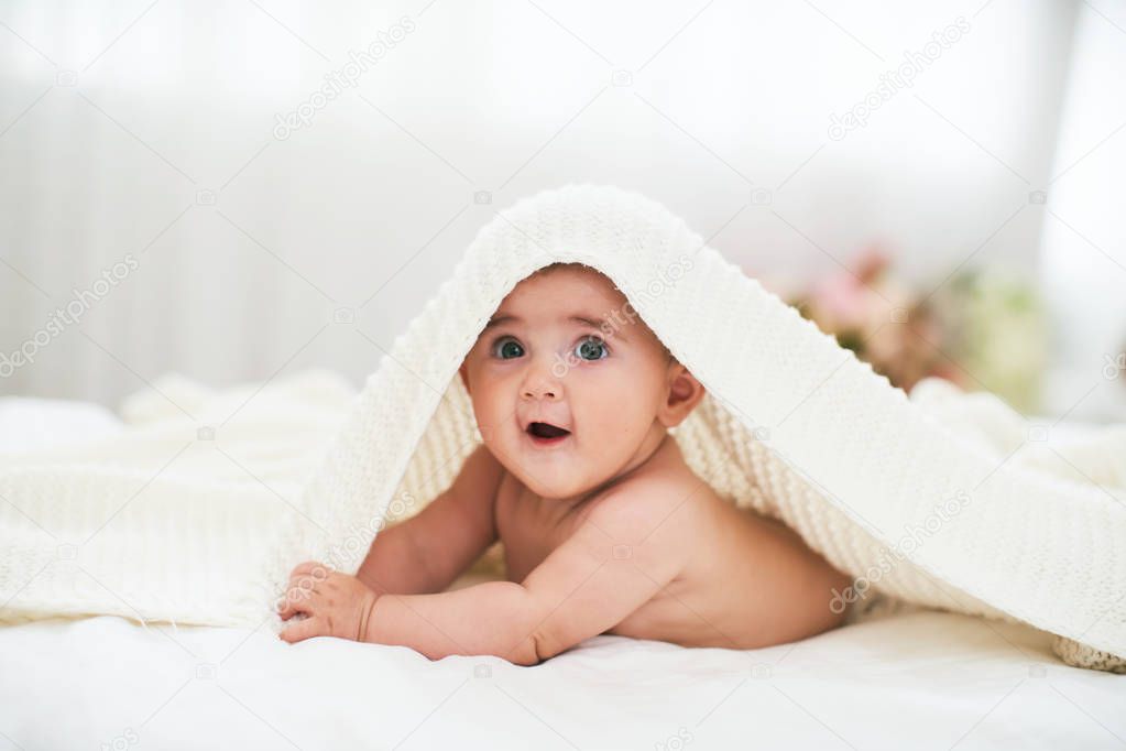 baby under the towel. a cheerful little child looks out from und