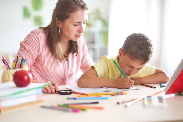 Madre aiuta il figlio a fare lezioni. scuola a casa, lezioni a casa . — Foto Stock