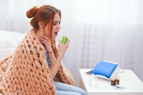 Das Mädchen sprüht das Spray in den Mund, behandelt Halsschmerzen. — Stockfoto