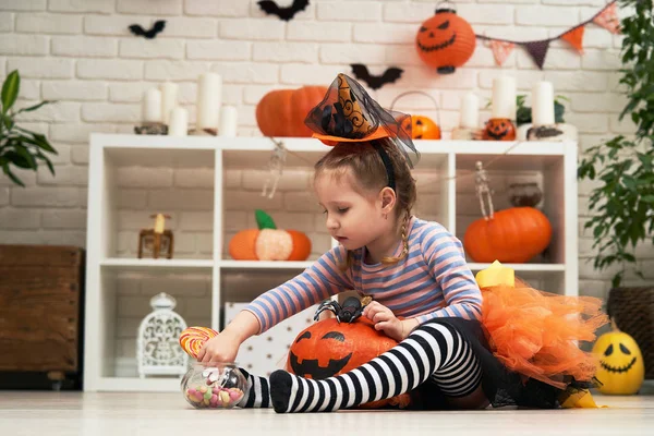 Uma menina em um traje de bruxa, recebe doces recebidos por Hallow — Fotografia de Stock