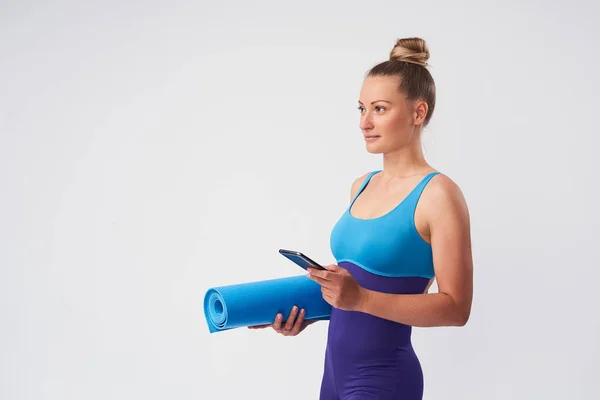 携帯電話と体操のためのマットを持つ若い運動女性 — ストック写真