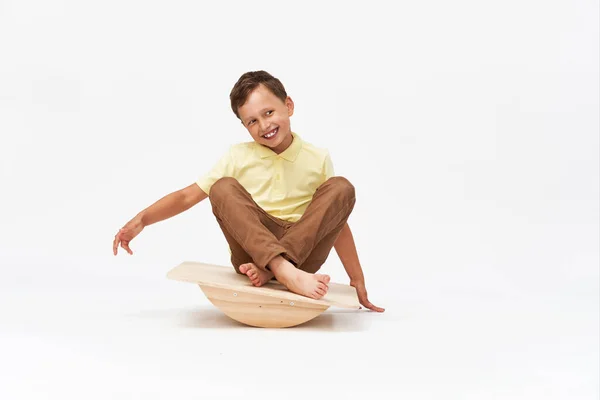 小男孩坐在一个特殊的模拟器上训练前庭装置 为了保持平衡 他举起双手坐下来 前庭器械的训练 平衡练习 — 图库照片