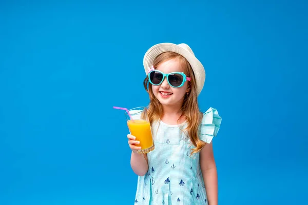 Menina Bonito Vestido Chapéu Óculos Sol Posa Fundo Azul Com — Fotografia de Stock