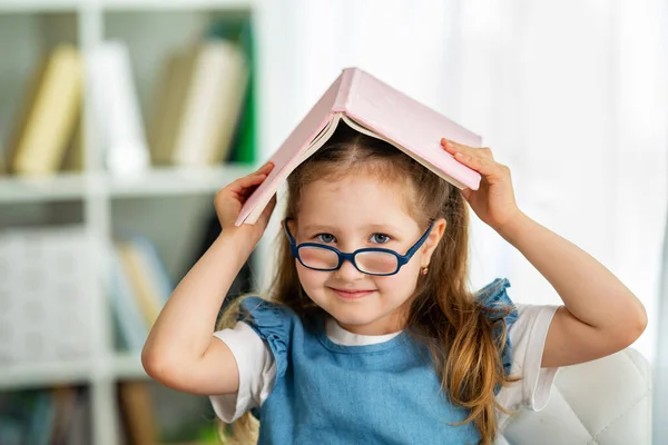 Close Portrait Funny Smiling Little Girl Glasses Book Her Head — Stock Photo, Image