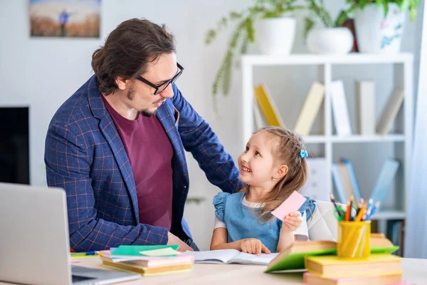 cute little girl is engaged in lessons with a teacher at home. Primary school tutor. Preschool education. Dad helps with homework. Individual training.