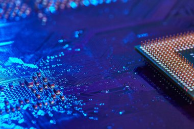 Bilgisayarın anakartında uzanan kontaklarla birlikte CPU masaüstü. Çip mavi ışıkla işaretlenmiş. Teknoloji geçmişi. Yakın çekim.