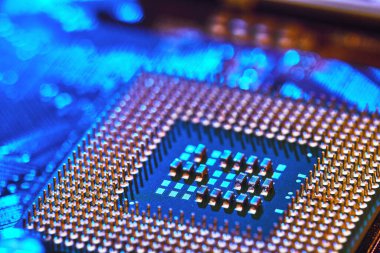 Bilgisayarın anakartında uzanan kontaklarla birlikte CPU masaüstü. Çip mavi ışıkla işaretlenmiş. Teknoloji geçmişi. Yakın çekim.