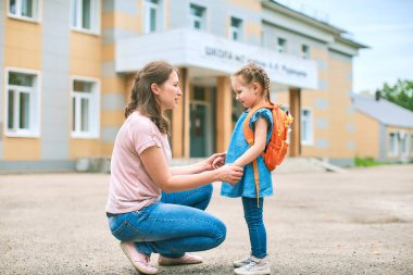 woman morally supports her daughter, holding hands, encourages the child. mother accompanies a student to school. a friendly family goes to kindergarten.happy little girl with a caring mother. clipart