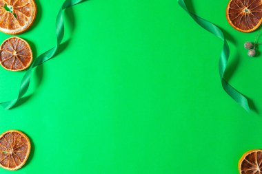 Yeşil arka planda kurumuş portakal dilimleriyle Noel kompozisyonu. Dekorasyon için doğal kuru gıda malzemesi. Metnin yerleşimi. Boşluğu kopyala.