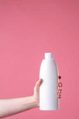 Bir kadının elinde bir aletle, ev kimyasallarıyla fotokopi çekilen pembe bir arka planda yakın plan fotoğrafı. Reklam, yıkama, temizlik, evrensel temizlik aracı.