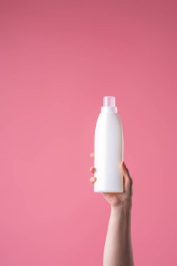 Bir kadının elinde bir aletle, ev kimyasallarıyla fotokopi çekilen pembe bir arka planda yakın plan fotoğrafı. Reklam, yıkama, temizlik, evrensel temizlik aracı.