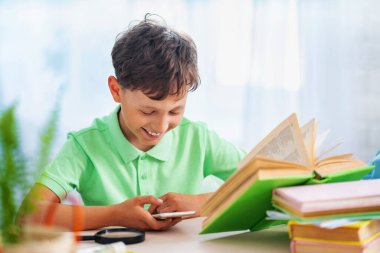 Tembel çocuk ev ödevi ve disiplin yerine hevesle akıllı telefondan oyun oynuyor. Sıkıcı küçük okul çocuğu ev ödevi yapmak yerine akıllı telefonuyla oynuyor. İnternet ve oyun bağımlılığı kavramı