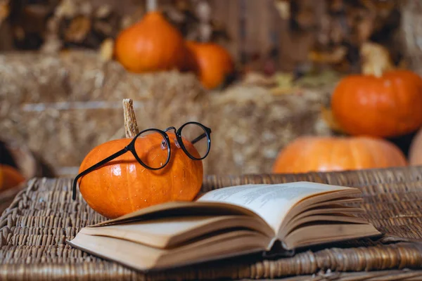 Halloween pumpkin on a wooden background, a festive decoration. The mood on Halloween. Happy Halloween. Pumpkin with glasses. vintage book with pumpkin and glasses autumn background