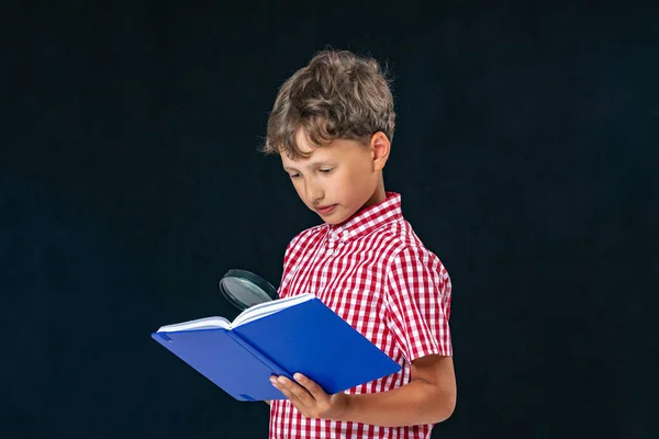 smart, attentive student holds book in his hands and writes something in it. child goes to school. student holds a backpack and book. Isolated on green background. Back to school. Copy space