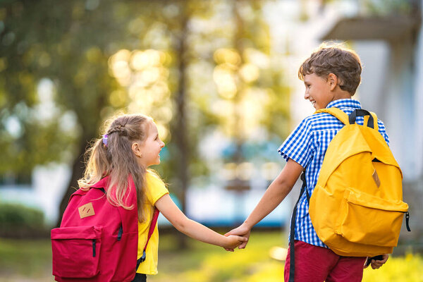 Primary school pupil. boy and girl with backpacks walking down street. Happy children happy to go back to school. beginning school year. Children in full growth, with joy went to school. rear view
