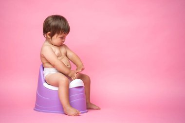 Lazımlıkta oturan bezli şirin bir bebek. Tuvalet ve tuvalet eğitimi. Küçük bir çocuk yararlı bir beceriye alışır. Hijyen. Bebek lazımlık lazımlığında oturuyor.