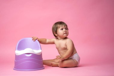 Lazımlıkta oturan bezli şirin bir bebek. Tuvalet ve tuvalet eğitimi. Küçük bir çocuk yararlı bir beceriye alışır. Hijyen. Bebek lazımlık lazımlığında oturuyor.