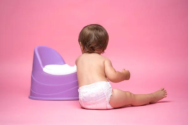 Cute baby in a diaper sitting on a potty. Toilet and potty training. A small child gets used to a useful skill. Hygiene.Baby sitting on a potty toilet stool potty