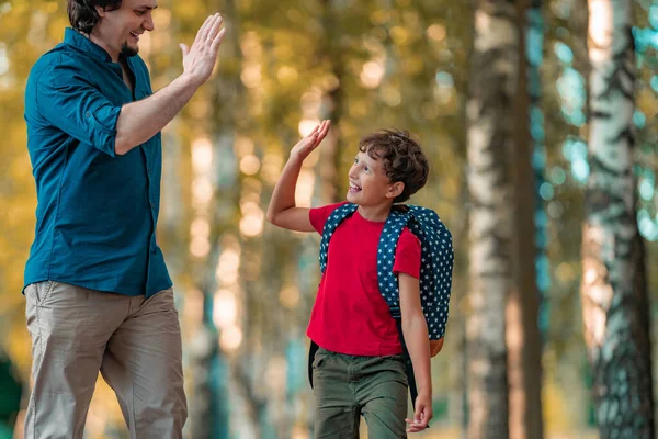 happy family of father and son a man holds the hand of a schoolboy son of a primary school student. Dad meets the child after school and goes for a walk together in the fresh air