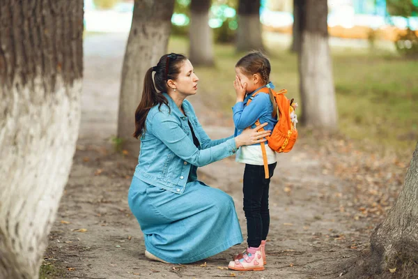 mom calms her daughter in street. child cries, woman comforts girl, walking in Park. Support. Protection childhood. mother explains rules of behavior to the child.