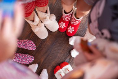 Altı çift ayak, şenlikli Noel çorapları giyip etrafta dolanıyorlar. Yukarıdan manzara. Noel atmosferi ve ruhu. Mutlu ailenin kutlaması. Boşluğu kopyala.