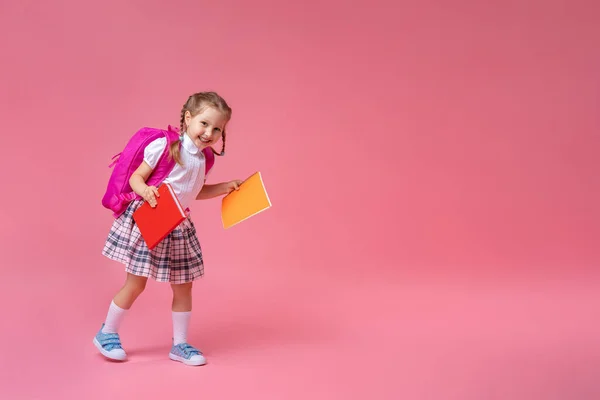 学校に戻って 制服を着たかわいい勤勉な子供ピンクの背景にジョギング バックパック付きの子供 女の子は学校に行く準備ができてる コンセプチュアル スクールに戻っていくダイナミックな映像 休日の始まり — ストック写真