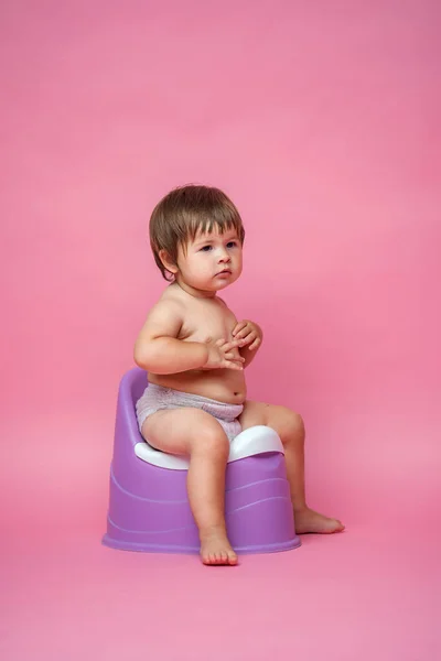 Cute baby in a diaper sitting on a potty. Toilet and potty training. A small child gets used to a useful skill. Hygiene.Baby sitting on a potty toilet stool potty