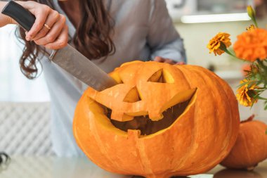 Bıçaklı kadın evde balkabağı ya da balkabağı oyuyor. Cadılar Bayramı için balkabağı oyulmuş balkabağı, dekorasyon ve tatil konsepti. Cadılar Bayramı Konsepti. Kapat..