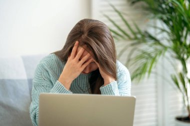 Yorgun, çok çalışan bir kadın dizüstü bilgisayarının başında otururken elleriyle yüzünü kapatıyor. Tükenmiş, bir hata yapmış, sorunlar. iş içeriği, finansal konsept