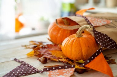 Sonbahar Şükran Günü geçmişi. Kabaklar ve renkli akçaağaç yaprakları beyaz masa manzaralı kağıt bir torbadan dökülüyor. Uzayı kopyala Sonbahar havası.