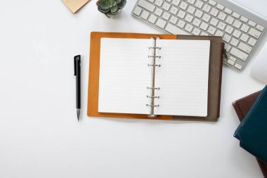 Kahverengi defter masanın üstünde, en üstte.