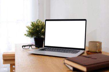 Beyaz bir evin içindeki çalışma masasına yerleştirilmiş boş ekranlı dizüstü bilgisayar..