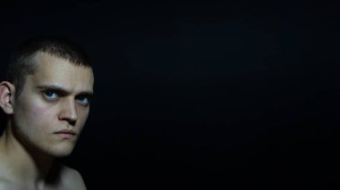 Siyah arka planda soldaki adamın yüzü.