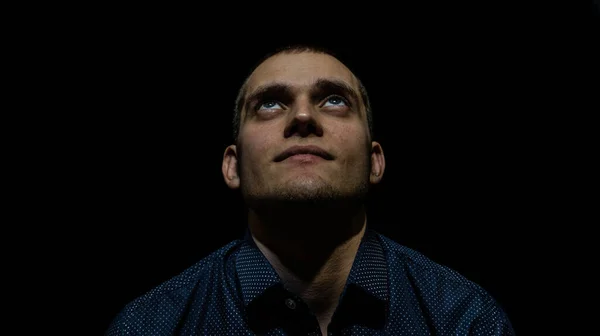 Siyah arka planda genç bir adamın portresi.