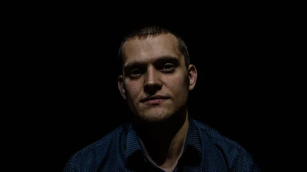 Siyah arka planda bir adamın portresi yukarı bakıyor.