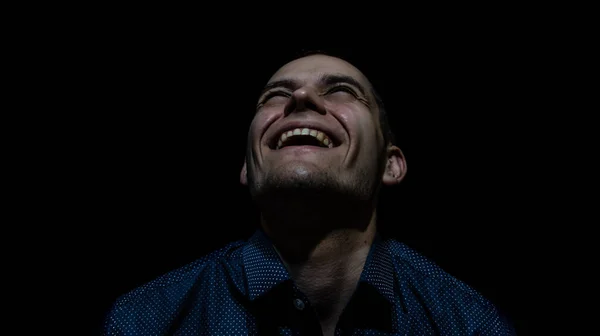 Siyah arka planda gülümseyen bir adamın portresi yukarı bakıyor.