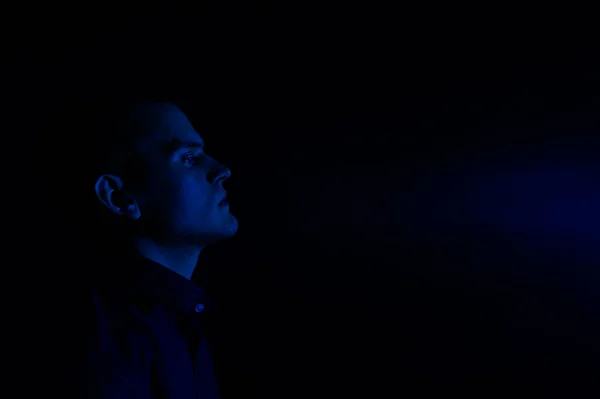portrait of a man in profile on a dark blue background
