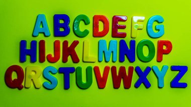 Açık yeşil zemin üzerinde plastiğin İngiliz alfabesini boya. eğitim