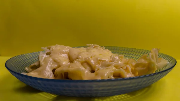 Tabakta peynirli kızarmış makarna. Sarı arkaplan