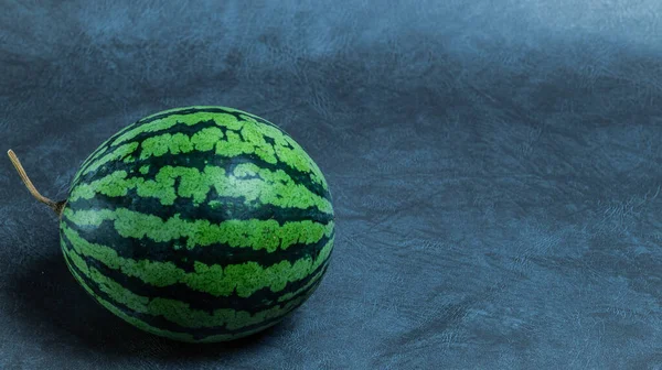 Gri arkaplanda yuvarlak yeşil karpuz