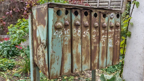 Eski Sovyet tarzı posta kutuları. Çim arka planında eski metal ve numaralandırılmış posta kutuları