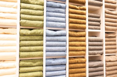 Satış mağazasındaki raflarda birçok renkli havlu katlanıyor. . 