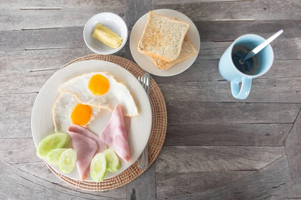 Frühstücksei Mit Schinken Auf Weißem Teller Und Kaffee Auf Holztisch — Stockfoto