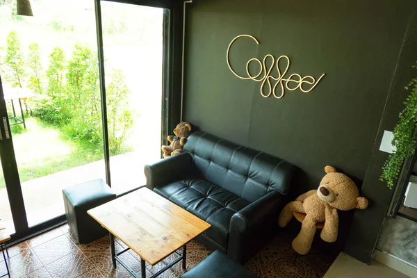 モダンなコーヒー ショップ装飾的な黒いソファと木製のテーブルと黒い壁の背景にネオンの光と書いてコーヒー単語内 — ストック写真