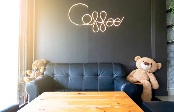 modern kahve dükkanı dekoratif siyah kanepe ve ahşap masa ve kahve kelime ile neon ışık siyah duvar arka plan üzerinde yazma içinde . 