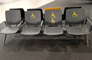 Istanbul, Turkey - August 13, 2025: An empty row of seats in an airport or train station waiting room. Some of the seats have yellow pictograms on them indicating seats for people with disabilities.