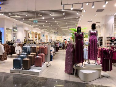 Istanbul, Turkey - August 13, 2025: Panoramic view of a modern and stylish clothing store. Mannequins in trendy summer purple dresses, and next to them a rack with various suitcases and travel bags.