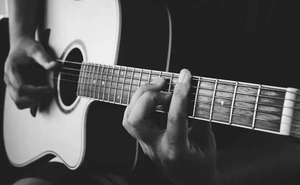 guitarist\'s hand on strings on dark background